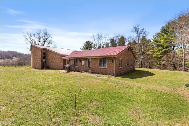 view of front of house with metal roof, a front lawn, and brick siding