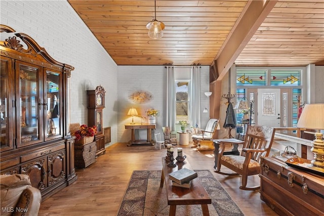 sitting room with vaulted ceiling, wood finished floors, wood ceiling, and brick wall