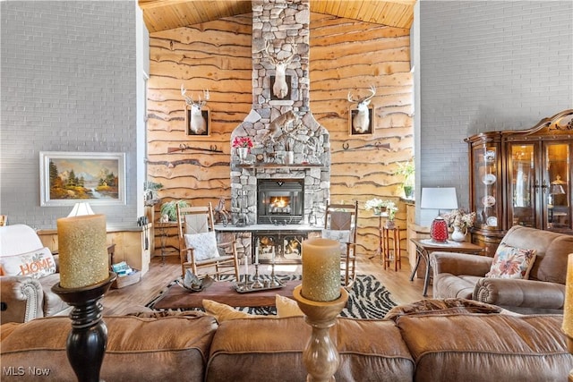 living room with a stone fireplace, high vaulted ceiling, wood finished floors, and wood ceiling