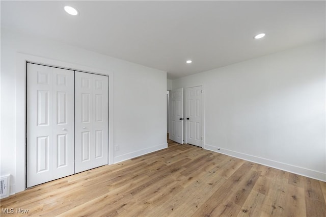 unfurnished bedroom with wood finished floors, baseboards, and recessed lighting