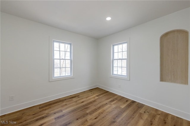 unfurnished room featuring baseboards, wood finished floors, and recessed lighting