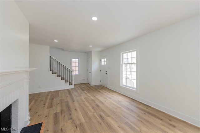 foyer entrance featuring stairs, recessed lighting, baseboards, light wood-style floors, and a brick fireplace