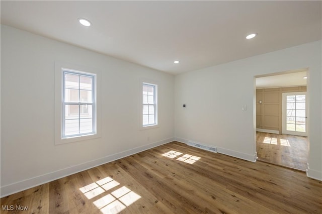 empty room featuring baseboards, visible vents, light wood-style flooring, and recessed lighting