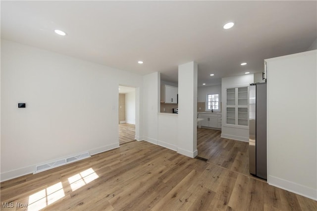 unfurnished living room with light wood-type flooring, recessed lighting, baseboards, and visible vents