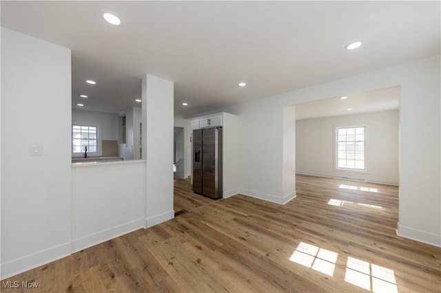 interior space featuring baseboards, light wood-style flooring, recessed lighting, and a sink