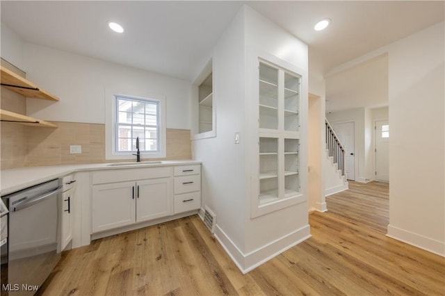 kitchen featuring light wood-type flooring, a sink, open shelves, and stainless steel dishwasher