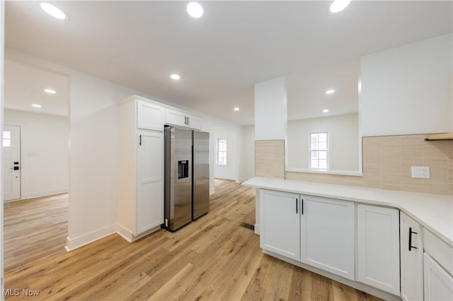 kitchen with white cabinets, light wood-style flooring, light countertops, stainless steel fridge, and recessed lighting