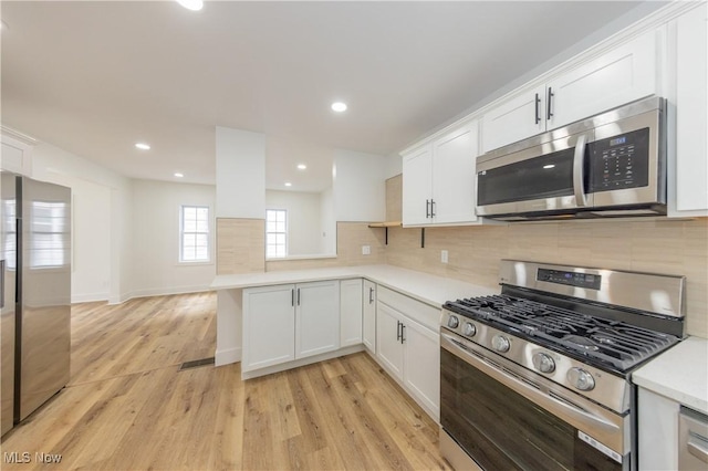kitchen featuring white cabinetry, light countertops, stainless steel appliances, and light wood-style floors