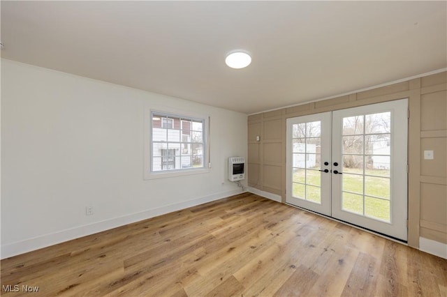 interior space with baseboards, heating unit, french doors, and light wood-style floors