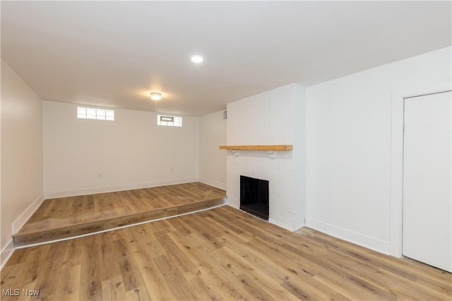 unfurnished living room featuring a brick fireplace, recessed lighting, baseboards, and light wood-type flooring