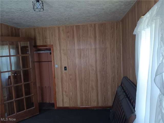 interior space featuring a textured ceiling and wood walls
