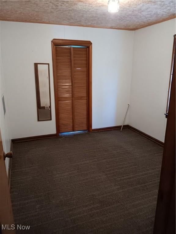 carpeted empty room featuring baseboards and a textured ceiling