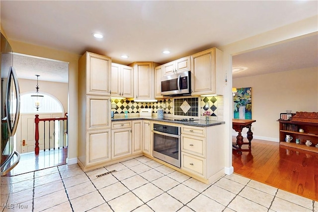 kitchen with tasteful backsplash, recessed lighting, light tile patterned floors, stainless steel appliances, and cream cabinets