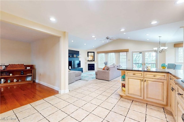 kitchen featuring ceiling fan with notable chandelier, a fireplace, lofted ceiling, and a wealth of natural light