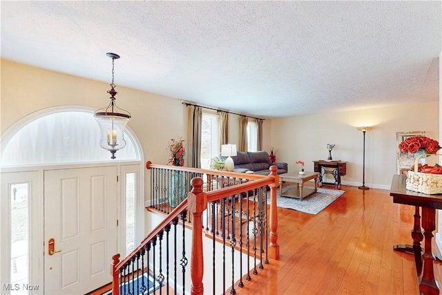 entrance foyer with baseboards, a textured ceiling, and light wood-style floors