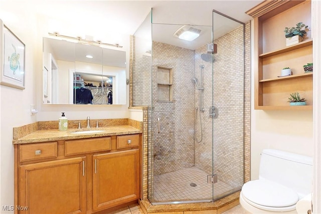 bathroom featuring a stall shower, a spacious closet, toilet, and vanity
