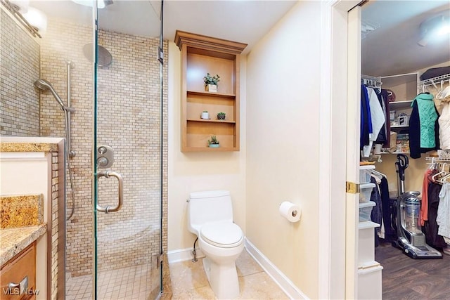 bathroom featuring toilet, a stall shower, a walk in closet, and vanity