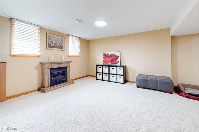living area with carpet floors, a glass covered fireplace, baseboards, and visible vents