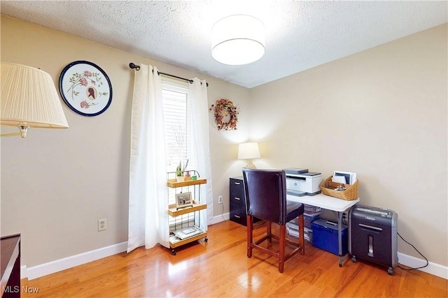 office area featuring a textured ceiling, baseboards, and wood finished floors