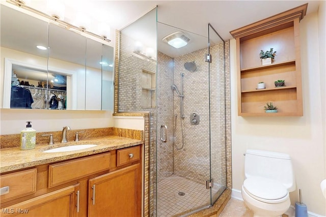 bathroom featuring toilet, vanity, a walk in closet, and a shower stall