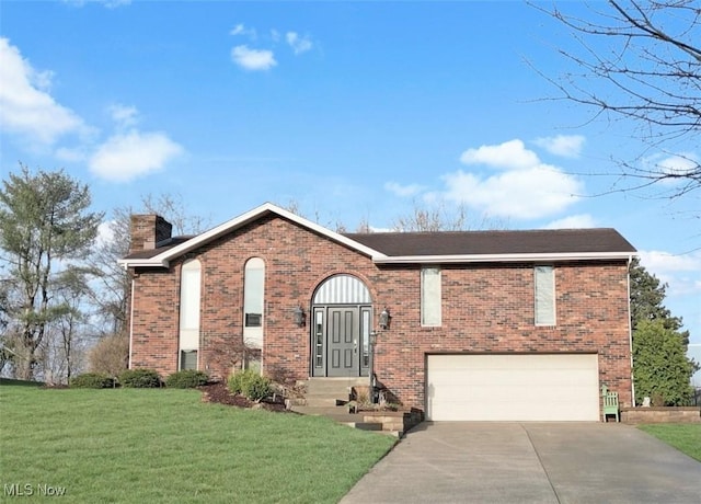 split foyer home featuring driveway, a front yard, a chimney, an attached garage, and brick siding