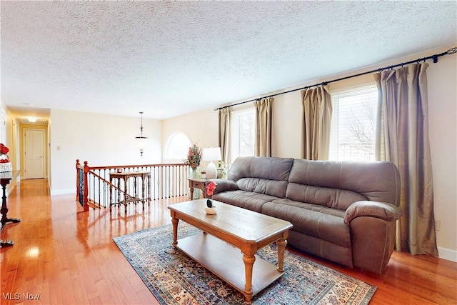 living area featuring baseboards, a textured ceiling, and light wood-style flooring