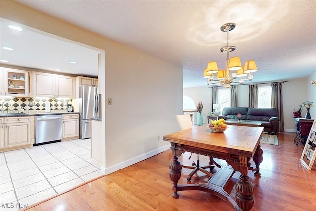 dining space with a notable chandelier, a textured ceiling, light wood-type flooring, baseboards, and recessed lighting