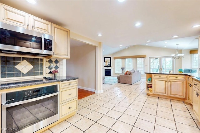 kitchen featuring tasteful backsplash, lofted ceiling, a healthy amount of sunlight, light tile patterned floors, and appliances with stainless steel finishes