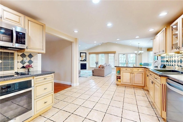 kitchen featuring light tile patterned floors, a sink, appliances with stainless steel finishes, and vaulted ceiling