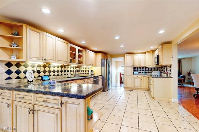 kitchen featuring light tile patterned floors, a sink, stainless steel appliances, and dark countertops