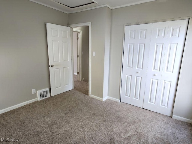 unfurnished bedroom with baseboards, a closet, carpet flooring, crown molding, and visible vents