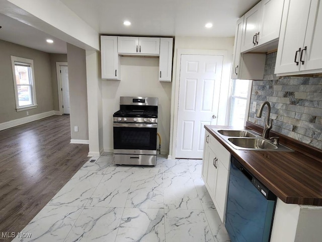 kitchen with baseboards, dishwasher, a sink, wooden counters, and stainless steel gas stove