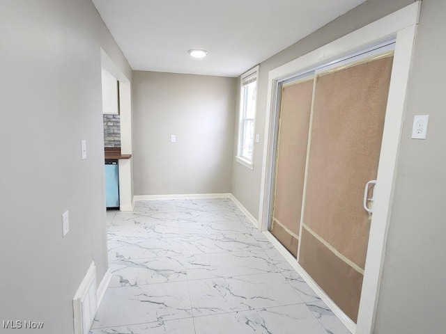 hall featuring marble finish floor, baseboards, and visible vents