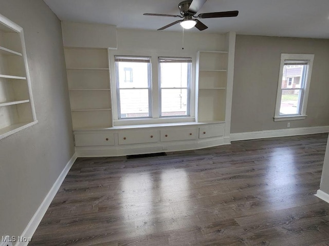 unfurnished room featuring dark wood-style flooring, ceiling fan, and a wealth of natural light