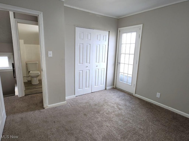 unfurnished bedroom with crown molding, carpet flooring, baseboards, and multiple windows