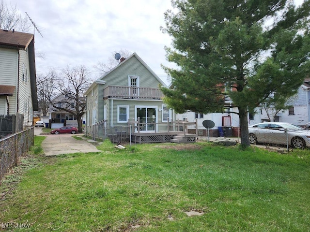 rear view of property featuring fence and a lawn