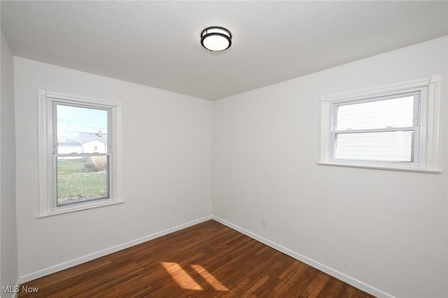 unfurnished room featuring dark wood-type flooring and baseboards