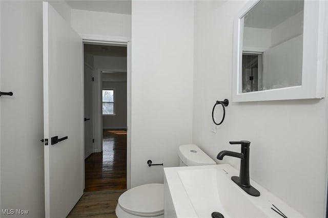 half bathroom featuring a sink, toilet, and wood finished floors