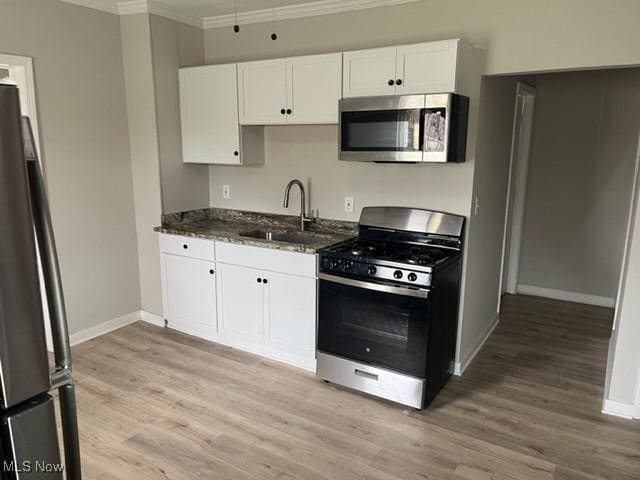1900 Lamoille Ct, Cleveland, OH 44113 - kitchen featuring appliances with stainless steel finishes, a sink, crown molding, light wood-type flooring, and baseboards