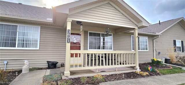 view of exterior entry with a porch and roof with shingles