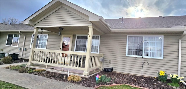 view of front facade with covered porch, central air condition unit, and roof with shingles