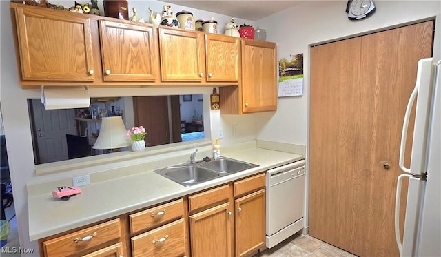 kitchen featuring white appliances, light countertops, brown cabinets, and a sink