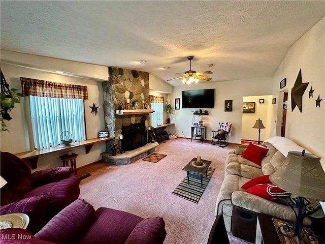 carpeted living room featuring a ceiling fan, a textured ceiling, a stone fireplace, and vaulted ceiling