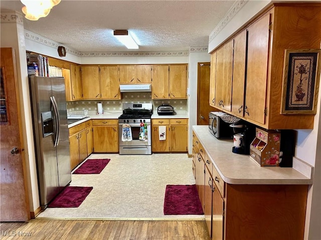 kitchen featuring appliances with stainless steel finishes, light countertops, brown cabinetry, and under cabinet range hood