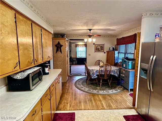 kitchen featuring a textured ceiling, brown cabinets, appliances with stainless steel finishes, ceiling fan, and light countertops