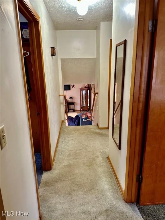 corridor with a textured ceiling and carpet floors