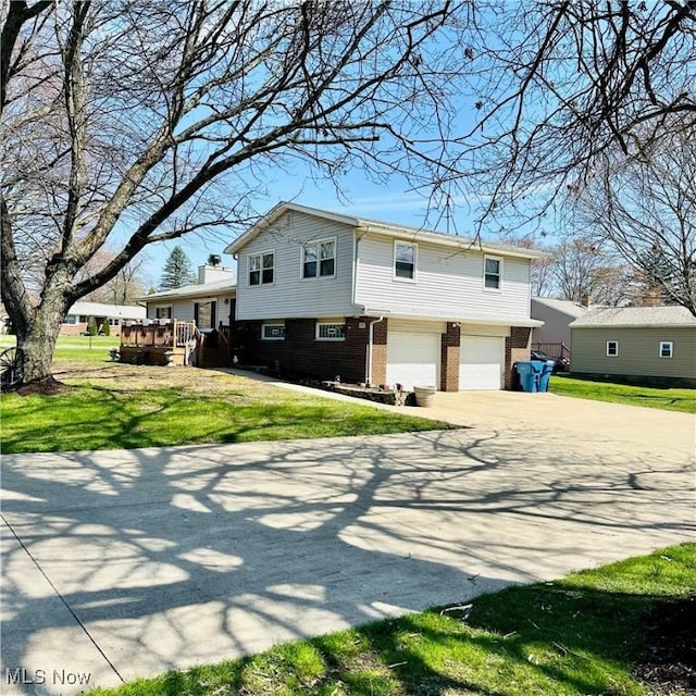 exterior space with a lawn, brick siding, concrete driveway, a deck, and an attached garage