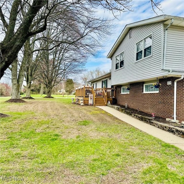 view of property exterior featuring brick siding, a wooden deck, and a lawn