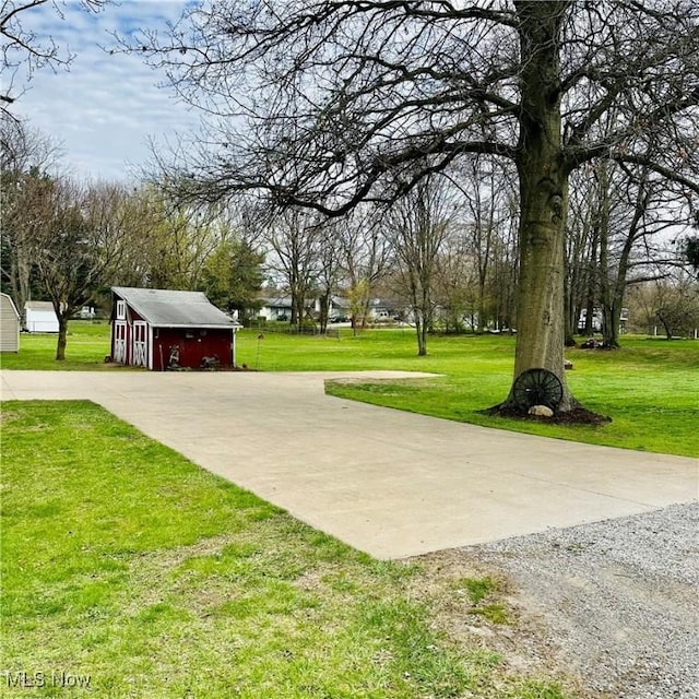 surrounding community featuring driveway, an outdoor structure, and a lawn