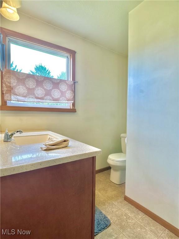 bathroom featuring baseboards, toilet, and vanity